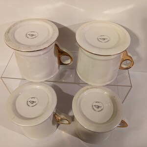 Pu&ograve; includere: Set di quattro tazze in ceramica bianca con bordo dorato e logo di un uccello dorato sul fondo.