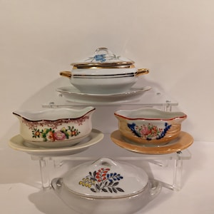 May include: Set of three white porcelain serving dishes with floral designs. The dishes have gold trim and are arranged on a tiered stand.