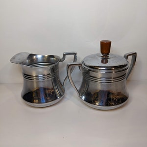 May include: A vintage silver creamer and sugar bowl set with a wooden knob on the lid of the sugar bowl.
