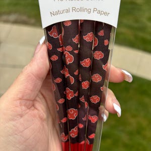 May include: A package of pre-rolled cones with a red and black cloud pattern. The package says "Pre-Rolled Cones Natural Rolling Paper".