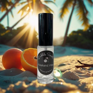 May include: A clear glass perfume bottle with a black cap, labeled "Weekend Vibes" by Dabble Scents, sits on a sandy beach next to an orange and a sliced orange. The background features a sunny beach scene with palm trees.