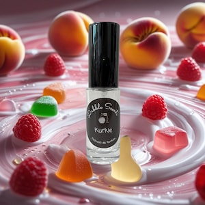 May include: A clear perfume bottle with a black cap, labeled "Dabble Scents Kurkie Extrait de Parfum," is surrounded by peaches, raspberries, and colorful gummy candies. The background features a pink and white swirl design.
