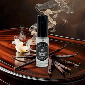 May include: A clear glass perfume bottle with a black cap, labeled "Mysterious Vanilla" with a vanilla bean design. The bottle is surrounded by vanilla beans and wisps of smoke on a dark wooden surface.