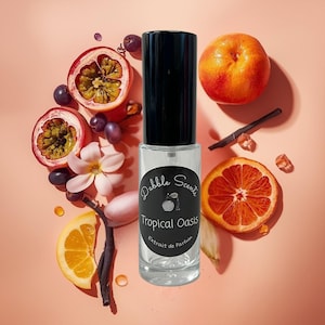May include: A clear perfume bottle with a black cap, labeled "Dabble Scents Tropical Oasis Extrait de Parfum." The image features passion fruit, grapes, orange slices, and a whole orange, with a pink background.