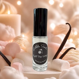 May include: A clear glass perfume roller bottle with a black cap and a circular black label. The label features the text Dabble Scents, an illustration of a perfume bottle, the text Fluff The What, and the text Extrait de Parfum.