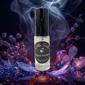 May include: A clear glass perfume bottle with a black cap. The label reads "Dabble Scents Magical Mayhem Extrait de Parfum". The background features purple and blue floral elements and a smoky effect.