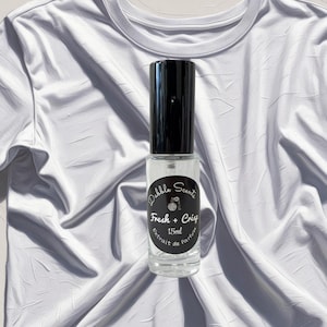 May include: A clear glass bottle with a black cap and label. The label reads "Dabble Scents Fresh + Crisp 15ml Extrait de Parfum".