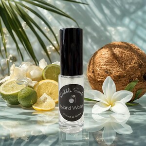 May include: A clear glass perfume bottle with a black cap and a circular label reading Dabble Scents Island Water Extrait de Parfum. The bottle is surrounded by a whole coconut, sliced limes, a lemon slice, and white tropical flowers.