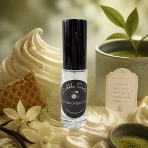 May include: A clear glass perfume bottle with a black cap and a circular label featuring the text Dabble Scents, Matcha Dream Cone, and Extrait de Parfum. The label also includes a small graphic of a perfume bottle and a waffle cone.
