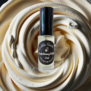 May include: A small glass bottle of perfume with a black cap and label. The label reads "Dabble Scents Confectionary Delight 15ml Extrait de Parfum".