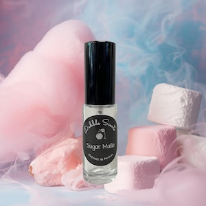 May include: A clear glass perfume bottle with a black cap, labeled "Sugar Mallo" by Pebble Scents. The bottle is surrounded by pink and white marshmallows and cotton candy against a blue and pink background.