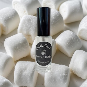 May include: A clear glass perfume bottle with a black cap, labeled "Mother Fluffer" by Dabble Scents, sits among large, white, sugar-dusted marshmallows. The bottle contains a clear liquid and has a black and white label.