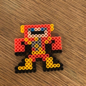 May include: A red, yellow, black, and blue robot made of small plastic beads. The robot has a round head, two arms, and two legs.