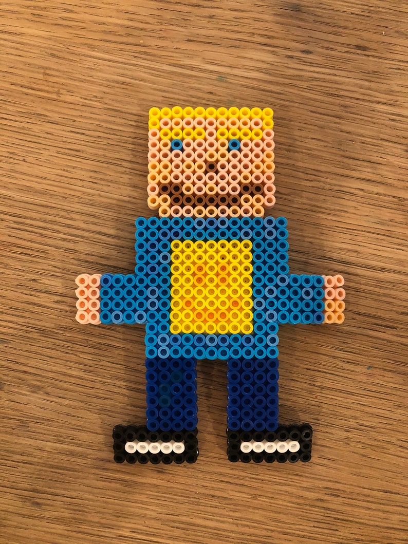 May include: A blue and yellow pixel art figure of a person with blonde hair, wearing a blue shirt with a yellow square on the front, blue pants, and black shoes.
