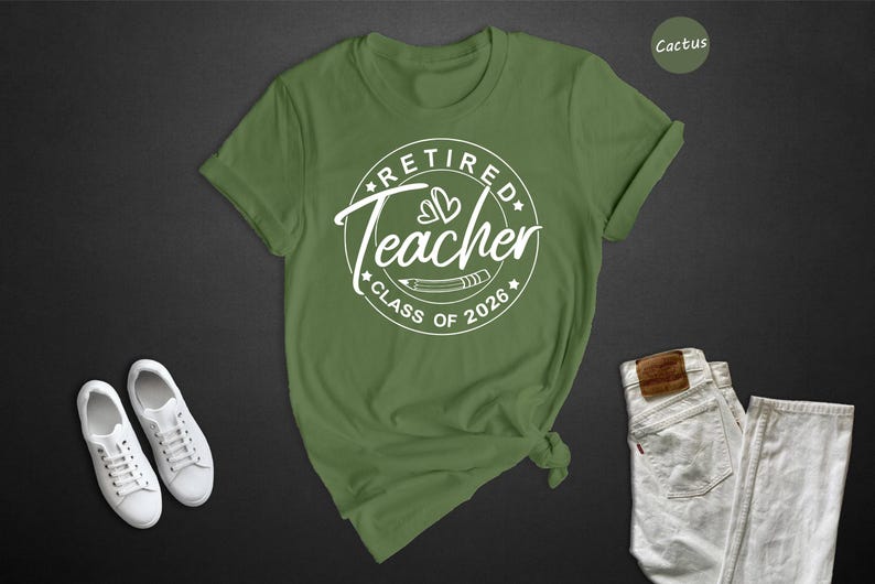 a green t-shirt with a white graphic design, a pair of white sneakers, and a pair of white jeans, all laid out on a dark background.
