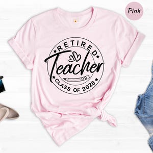a pink t-shirt with a graphic design, a pair of blue jeans, and some accessories such as a perfume bottle and a pair of shoes, all laid out on a white background.