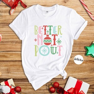 May include: White t-shirt with the text 'Better Not Pout' in colorful letters with a Christmas ornament design. The text is in a festive font with snowflakes and other Christmas-themed decorations.
