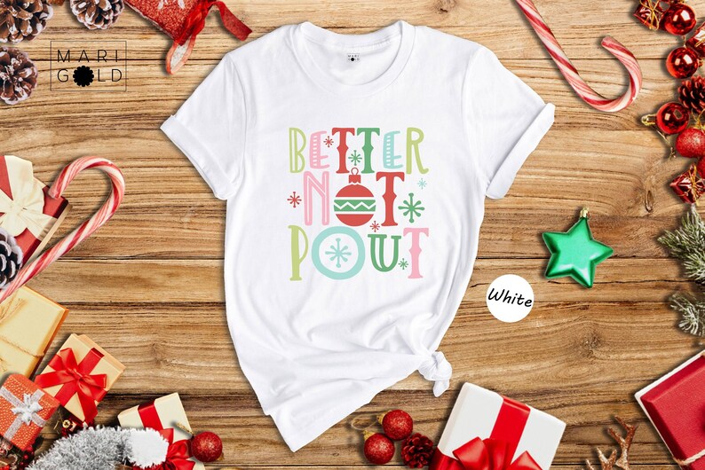 May include: White t-shirt with the text 'Better Not Pout' in colorful letters with a Christmas ornament design. The text is in a festive font with snowflakes and other Christmas-themed decorations.