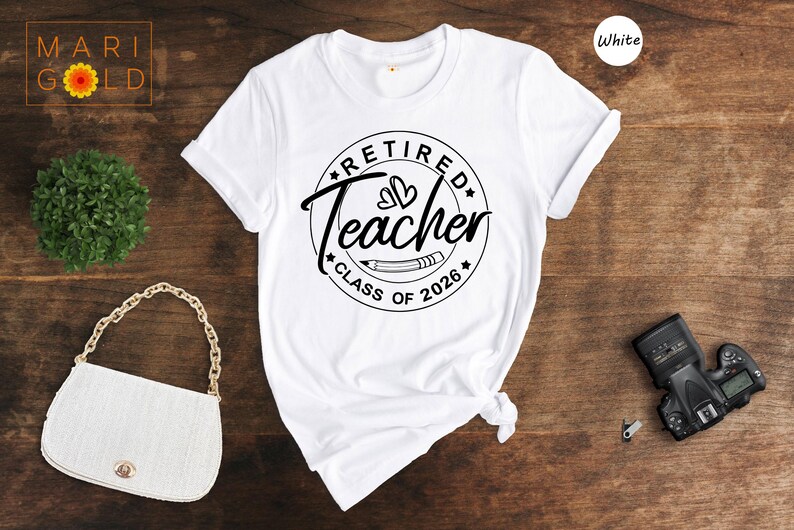 a white t-shirt with a graphic design, a white purse, a camera, and a plant on a wooden surface.