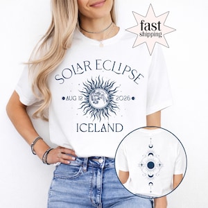 May include: White t-shirt with a navy blue solar eclipse design. The design includes the text "SOLAR ECLIPSE AUG 12 2026 ICELAND" and a sun and moon graphic. The back of the shirt features a matching celestial design.