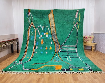 May include: A green Moroccan rug with a unique abstract design featuring colorful geometric shapes and lines. The rug has a fringe border and is made of wool.