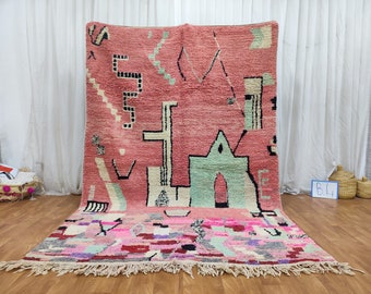 May include: A pink and green Moroccan rug with geometric patterns and a fringe border. The rug has a unique abstract design with a mix of colors and textures.