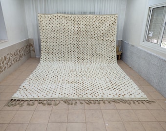 May include: A white and brown Moroccan rug with a tufted texture and fringe. The rug has a geometric pattern of small brown dots on a white background.