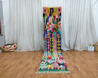 May include: A long, colorful Moroccan rug with a geometric pattern in shades of pink, blue, green, yellow, and orange. The rug has a fringe on both ends.