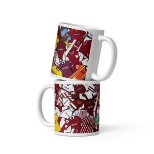 Peut inclure: Deux mugs en céramique blanche empilés l'un sur l'autre. Les mugs sont recouverts d'un collage de maillots de football de différentes couleurs, dont le bordeaux, le blanc, le jaune et le bleu. Les mugs ont des anses blanches.