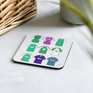 May include: A white coaster with a collection of nine green, purple, and white football jerseys. The jerseys have different designs and logos, including "P.D.  Sportswear", "Bukie", and "CAJON".