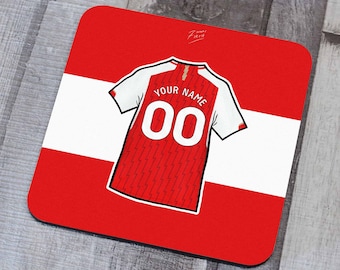 May include: Red and white personalized soccer jersey coaster with the text "YOUR NAME" and the number "00" on the back.