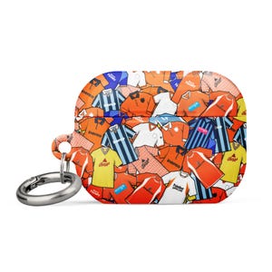 Könnte beinhalten: AirPods Pro-Hülle mit einem Muster aus Fußballtrikots in Orange, Weiß, Blau und Gelb. Die Hülle hat einen silbernen Karabinerhaken. Die Trikots zeigen Logos und Text. Die Hülle schützt die AirPods.