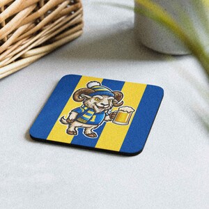 Peut inclure: Un dessous de verre carré avec un dessin de mouton de dessin animé portant un chapeau et une écharpe bleus et jaunes, tenant une chope de bière. Le dessous de verre a un fond rayé bleu et jaune.