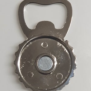 May include: Silver bottle opener with a magnetic back. The opener has a classic design and is perfect for opening bottles of beer or soda.