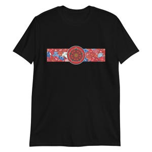 May include: Black t-shirt featuring a horizontal design with a red rose emblem in the center. The design includes a red, white, and blue pattern. The shirt is a short-sleeved crew neck.