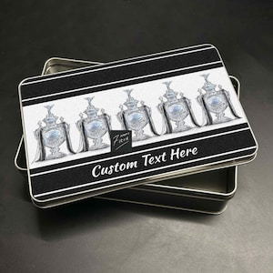 May include: A rectangular metal tin with a black and white striped design. The lid features illustrations of silver trophies and the text "Custom Text Here". The tin is open, revealing its interior.