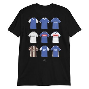 May include: Black t-shirt with a collage of nine different football jerseys. The jerseys are in various colors, including blue, white, and red, and feature different sponsors, including "Pioneer" and "Greene King".
