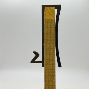 May include: A black metal bracket with a curved design is attached to a wooden post. The bracket has a small hook on the side.