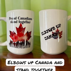 Peut inclure: Deux tasses en céramique blanches avec du texte noir et un motif de feuille d'érable rouge. Une tasse indique "Proud Canadians stand together" et l'autre "Elbows Up Canada". Les tasses ont une anse sur le côté.