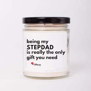 May include: A white candle in a glass jar with a black lid. The label reads "being my STEPDAD is really the only gift you need" with a red heart and the name "Tiffany".