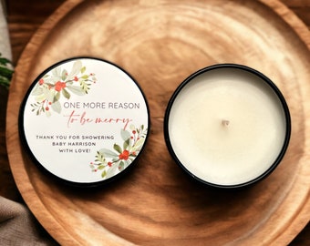 May include: A white candle with a black lid and a red and green floral design label that reads "ONE MORE REASON to be merry THANK YOU FOR SHOWERING BABY HARRISON WITH LOVE!"