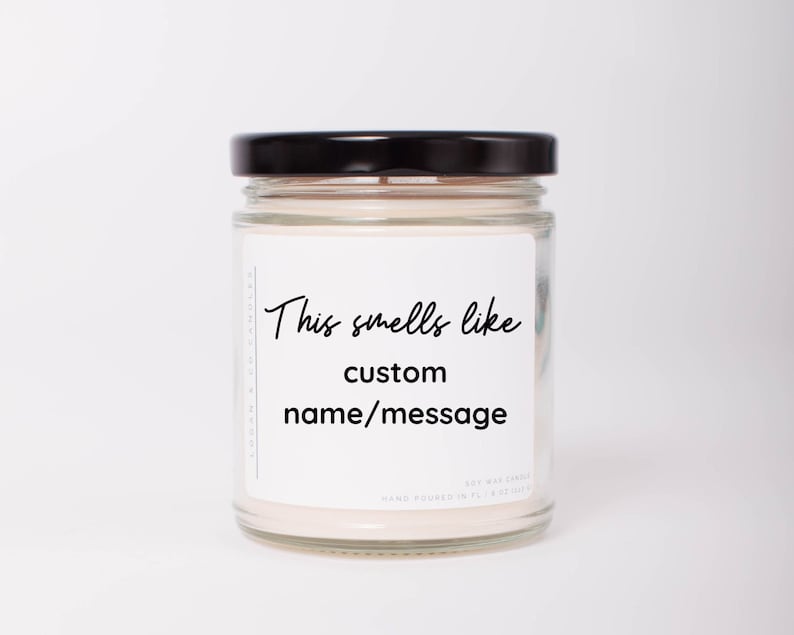 May include: A clear glass jar candle with a black lid. The label reads "This smells like custom name/message".