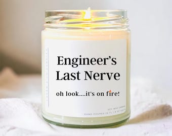 May include: A lit soy wax candle in a clear glass jar. The label reads "Engineer's Last Nerve" with the phrase "oh look....it's on fire!". The candle is hand-poured and contains 8 fl oz (237 ml) of wax.