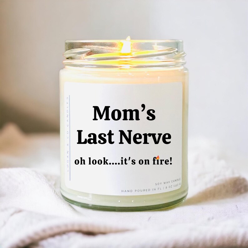 May include: A white soy wax candle in a glass jar with a black label that reads "Mom's Last Nerve oh look....it's on fire!"