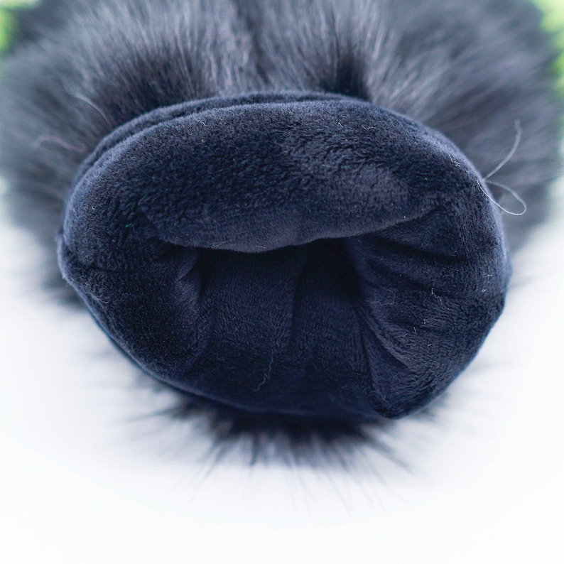 May include: Close-up of the inside of a black faux fur pom pom hat. The hat is lined with a soft, dark blue fleece fabric.