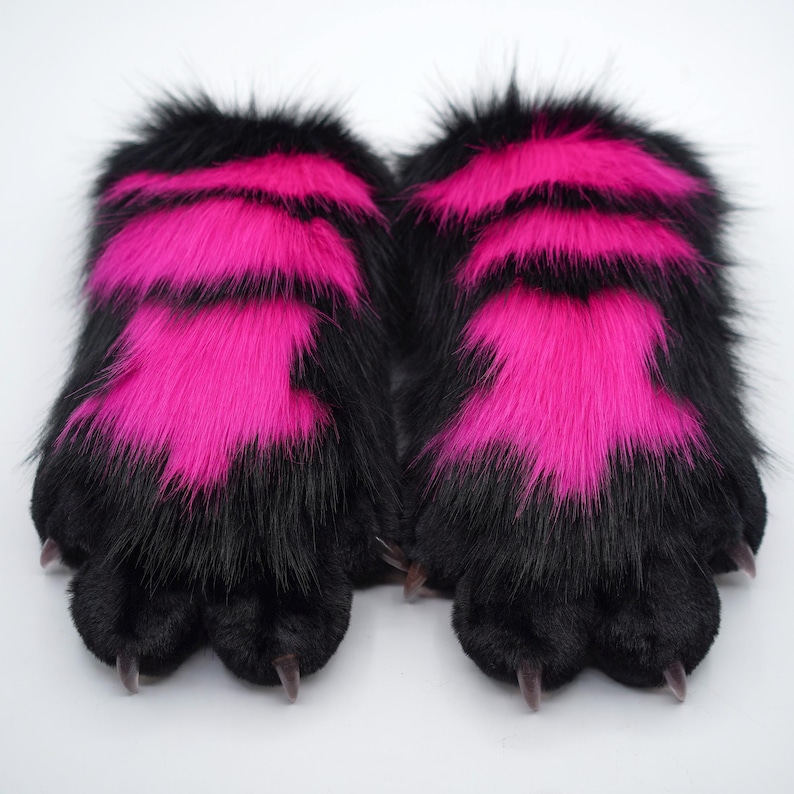 May include: A pair of black and pink furry paw-shaped hand warmers with black claws.