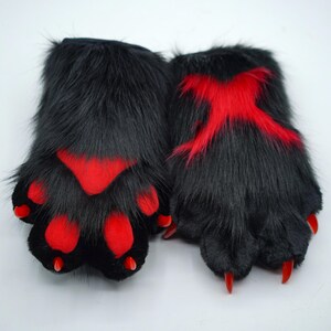 May include: A pair of black furry hand paws with red accents. The paws have claws and are designed to look like animal paws.