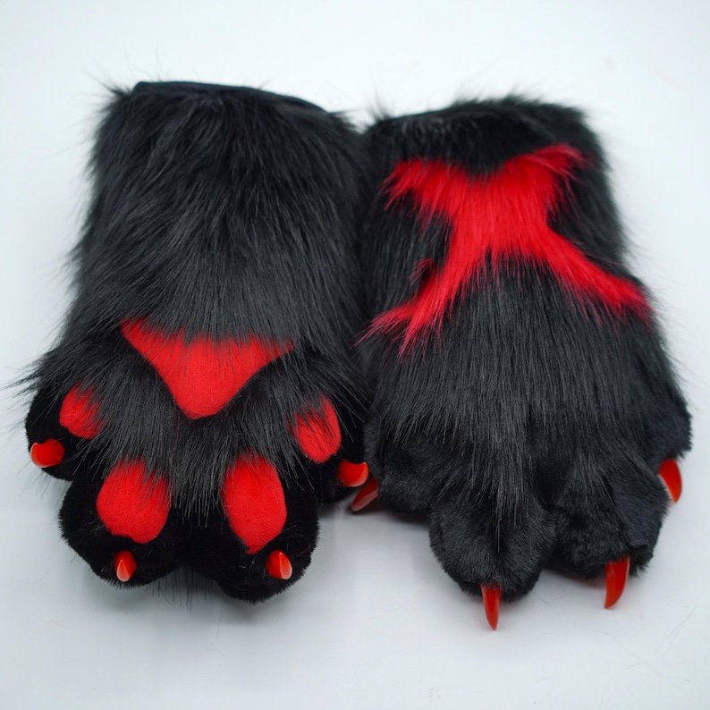 May include: A pair of black furry hand paws with red accents. The paws have claws and are designed to look like animal paws.