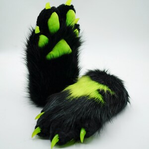 Puede incluir: Un par de patas peludas negras con garras verdes y almohadillas verdes. Las patas est&aacute;n dise&ntilde;adas para parecer patas de animales.