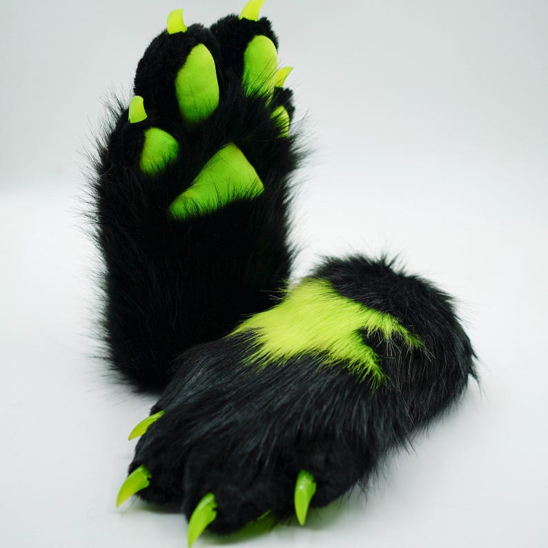 Puede incluir: Un par de patas peludas negras con garras verdes y almohadillas verdes. Las patas est&aacute;n dise&ntilde;adas para parecer patas de animales.